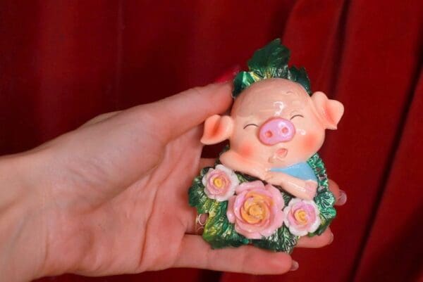A person holding a pig figurine in their hand.