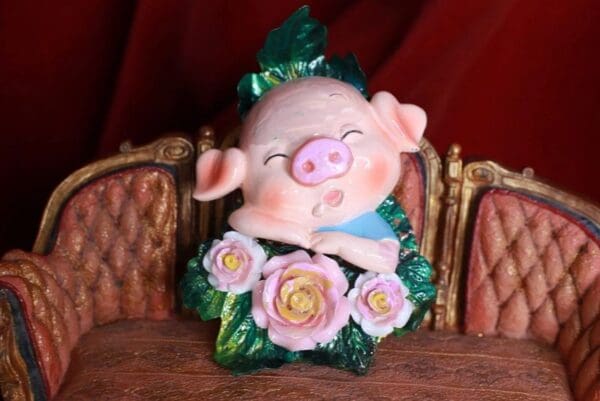 A pig figurine sitting on top of some leaves.