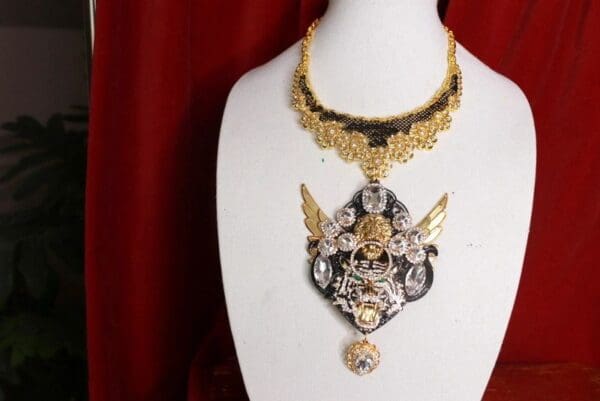 A necklace with a gold chain and a black ribbon