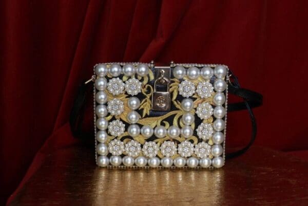 A purse with pearls and gold flowers on it.