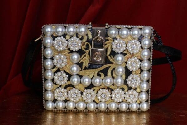 A purse with pearls and flowers on it.