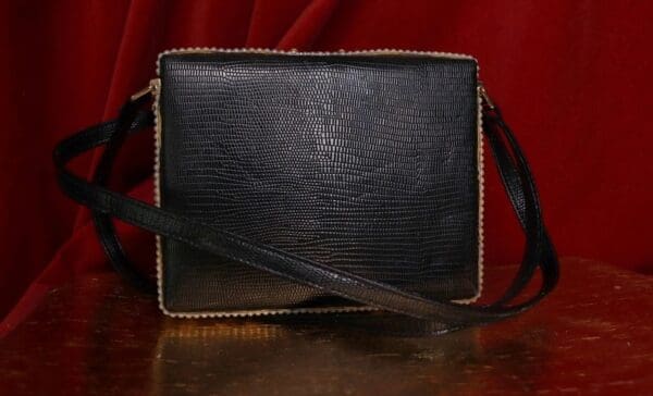 A black bag with brown trim on top of a table.