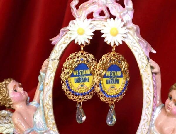 A pair of earrings with the words " we stand outside ".