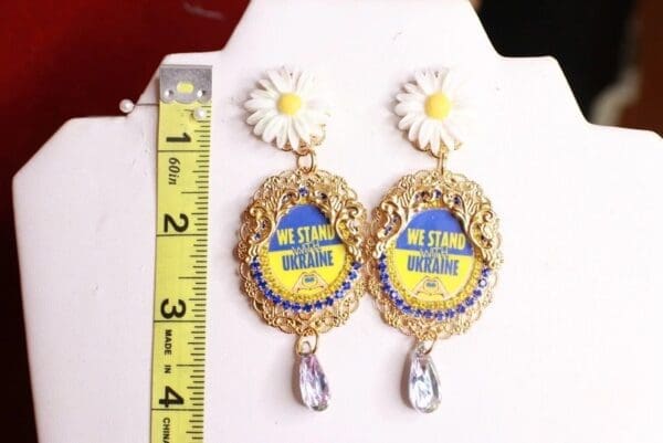 A pair of earrings with a flower and a ruler