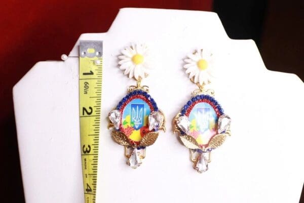A pair of earrings with a flower and a bird on them.