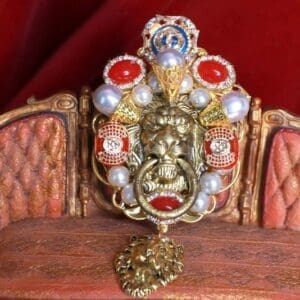 A gold mask with red and white jewels on top of it.