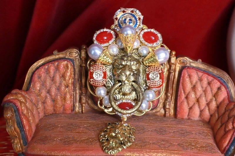 A gold mask with red and white jewels on top of it.