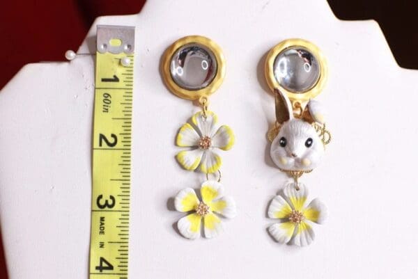 A pair of earrings with a mirror and flowers.