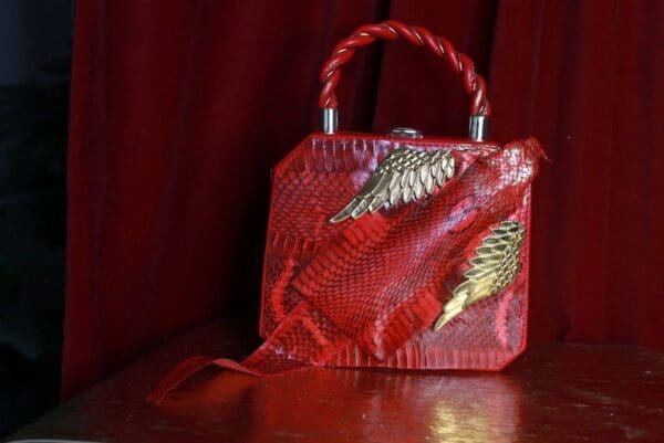 A red purse sitting on top of a wooden table.
