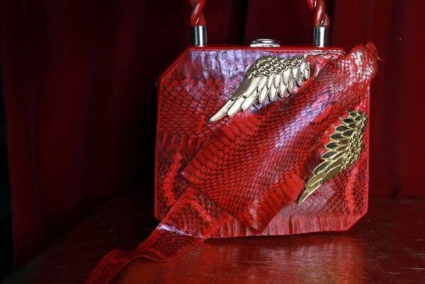 A red purse with gold wings on it.