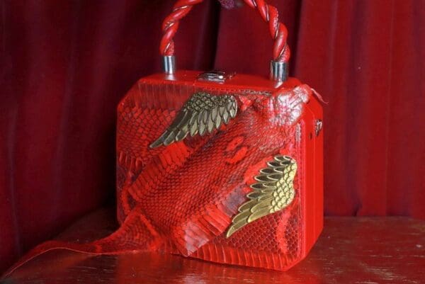 A red purse with gold wings on it.