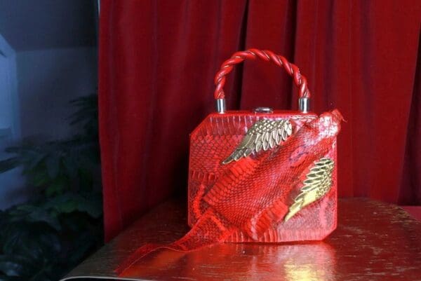 A red purse with gold leaves on it.