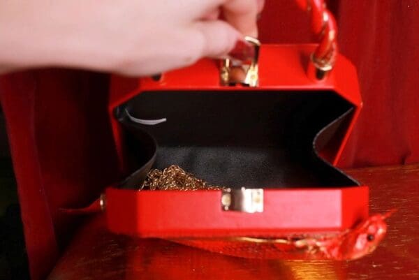 A red purse with gold jewelry inside of it.