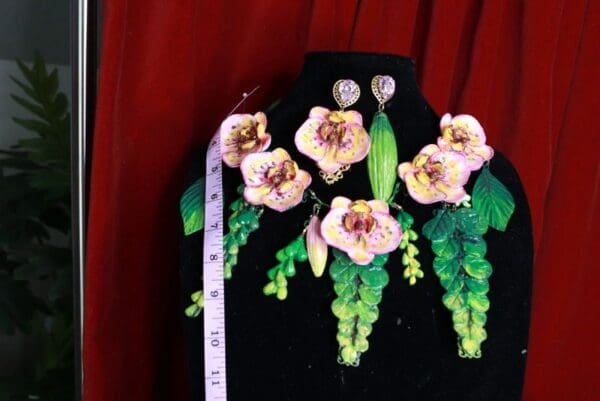 A black mannequin with some flowers and green leaves