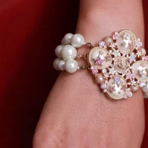 A woman wearing a bracelet with pearls and rhinestones.