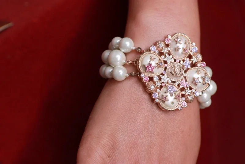A woman wearing a bracelet with pearls and rhinestones.