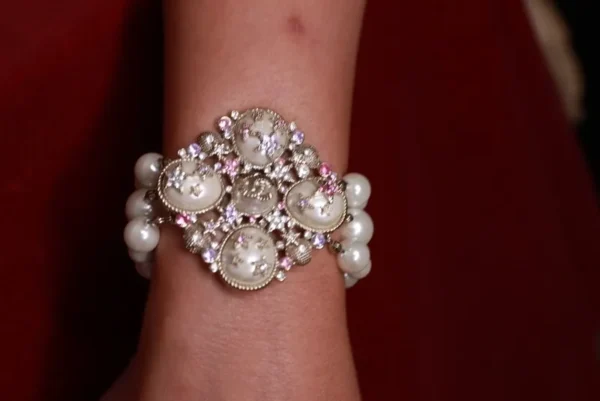 A woman wearing a bracelet with pearls and rhinestones.
