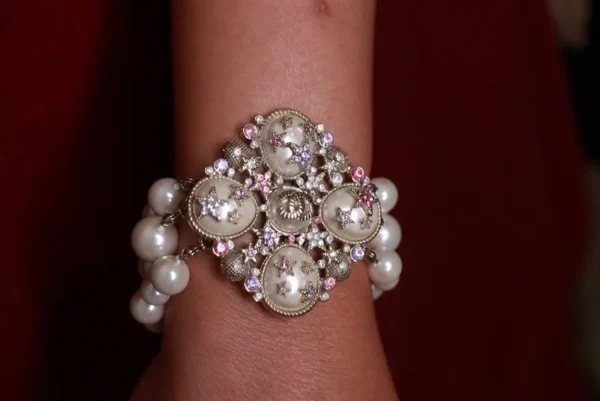 A bracelet with pearls and a flower on it.