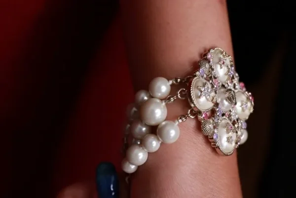 A woman wearing a bracelet with pearls and rhinestones.