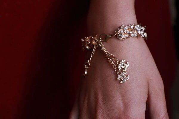 A woman 's hand wearing a bracelet with chains.