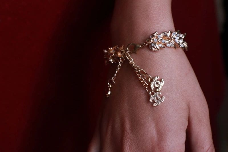 A woman 's hand wearing a bracelet with chains.