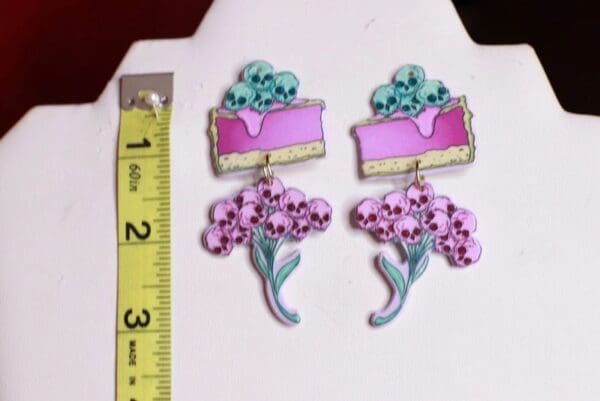 A pair of earrings with flowers and cake on them.