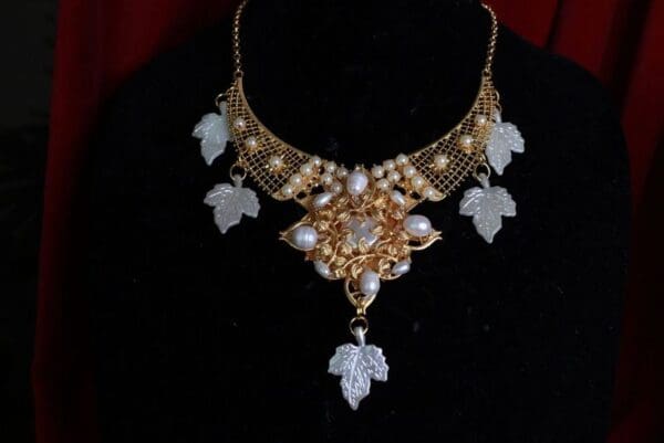 A necklace with leaves and pearls on it.