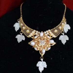 A necklace with leaves and pearls on it.