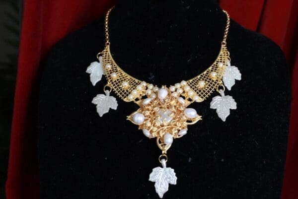 A necklace with leaves and pearls on it.