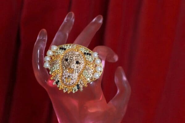 A hand holding a ring with pearls and diamonds.