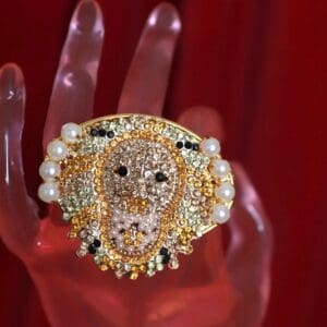 A hand holding a ring with pearls and diamonds.