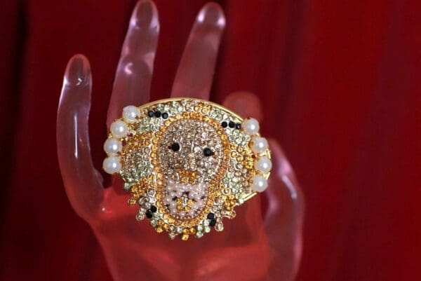 A hand holding a ring with pearls and diamonds.