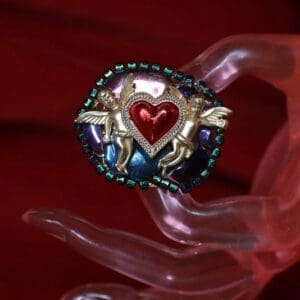 A hand holding a heart shaped object with two horses on it.
