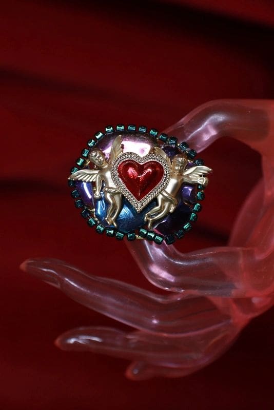 A hand holding a heart shaped object with two horses on it.
