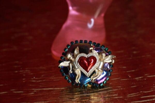 A red heart with angels around it on top of a table.