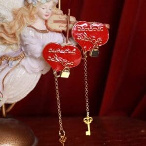 A pair of red heart earrings with gold key charms.