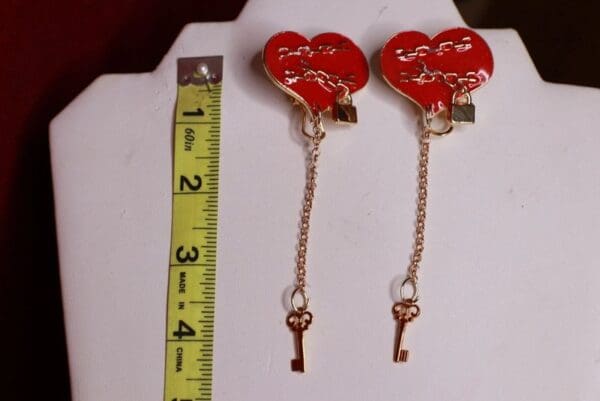 A pair of heart shaped earrings with key dangles.