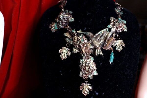 A necklace with leaves and birds on it.