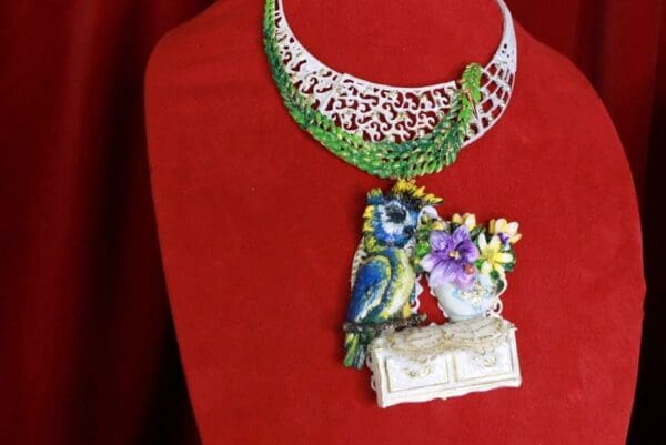 A necklace with two birds and flowers on it.