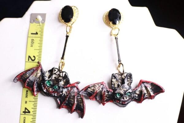 A pair of bat earrings with black and red bats.