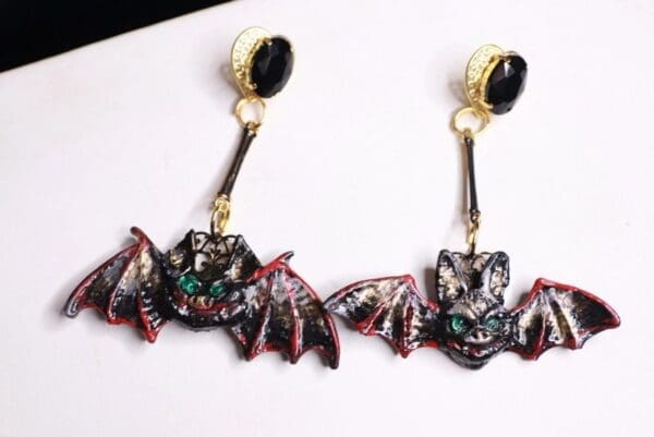 A pair of bat earrings hanging on top of a white board.