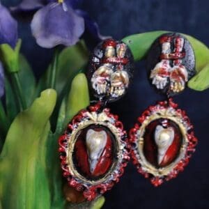 A pair of earrings with red and silver designs.