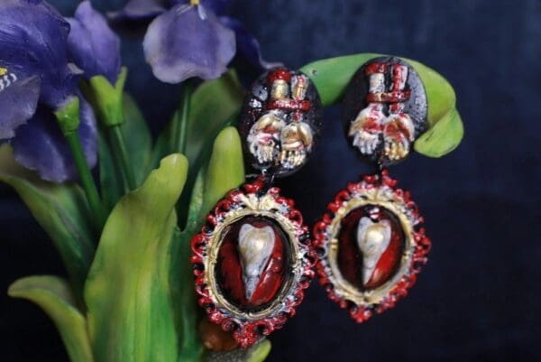 A pair of earrings with red and silver designs.