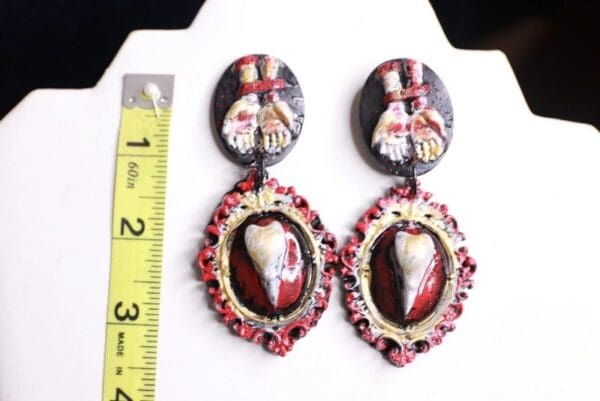 A pair of earrings with a heart and two people on them.