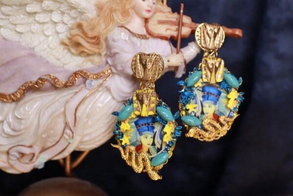 A pair of earrings with a picture behind it.