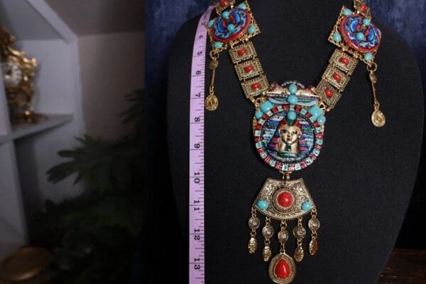 A woman wearing a necklace with an egyptian design.