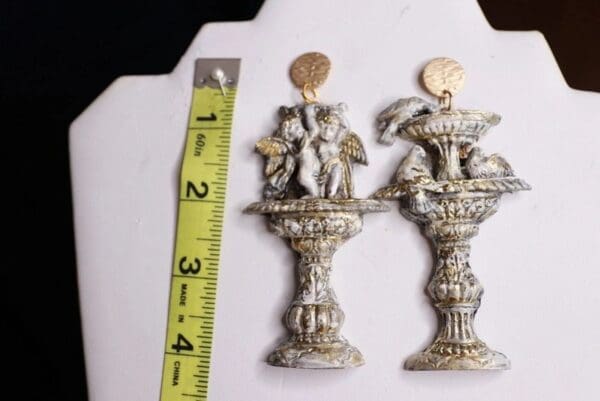 A pair of silver and gold candle holders with a ruler