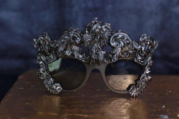 A pair of sunglasses with silver frames on top of a wooden table.