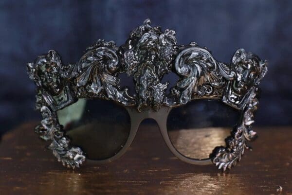 A pair of sunglasses with ornate frames on top.