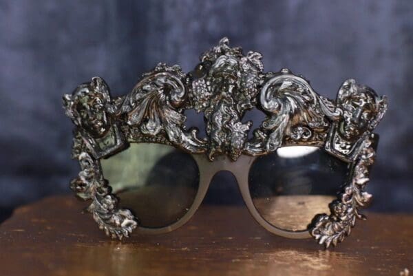 A pair of sunglasses with ornate frames on top.